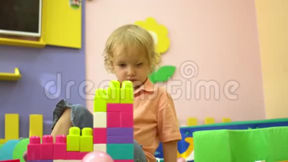 金发学龄前幼儿在幼儿园玩多种颜色的积木儿童发展视频的预览图