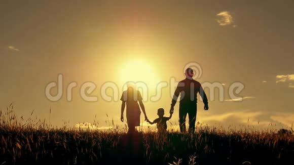 母亲和父亲在日落时与孩子散步的剪影视频的预览图