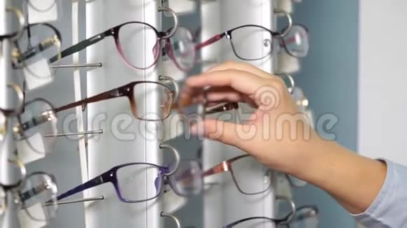 女孩正在光学沙龙的一个货架上检查眼镜的框架特写视频的预览图