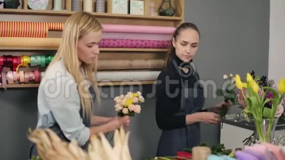穿着围裙的漂亮金发女子站在鲜花店的柜台旁一边整理鲜花视频的预览图