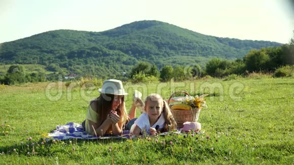 一个和母亲在一起的女孩躺在草地上手里拿着小花唱歌视频的预览图