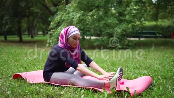 一个身穿罩袍的穆斯林妇女做伸展臀部肌肉的运动视频的预览图