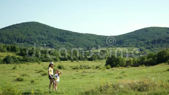 母亲和女儿在宽阔的草地上妈妈指着风景视频的预览图