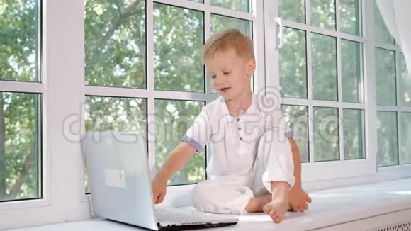 窗台上有笔记本电脑的小男孩视频的预览图