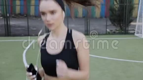 美丽的女人戴着耳机奔跑视频的预览图
