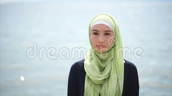 一位穆斯林妇女站在海边沉思的画像视频的预览图