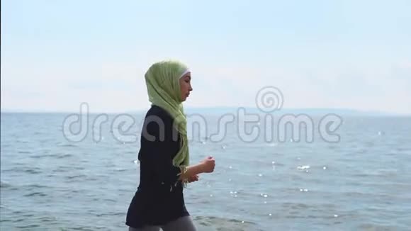 夏天一位年轻的穆斯林妇女在海边或海边参加体育活动视频的预览图