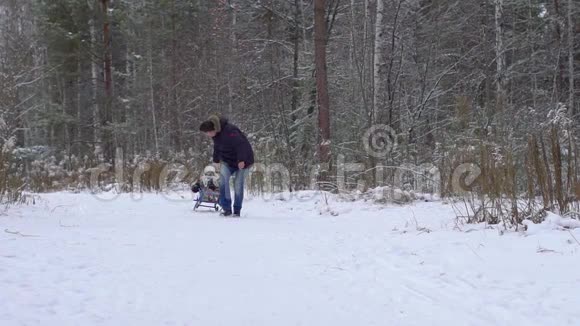 冬天的乐趣雪家人在冬天的时候雪橇父亲把他快乐的儿子卷在公园的雪橇上冬季温暖视频的预览图