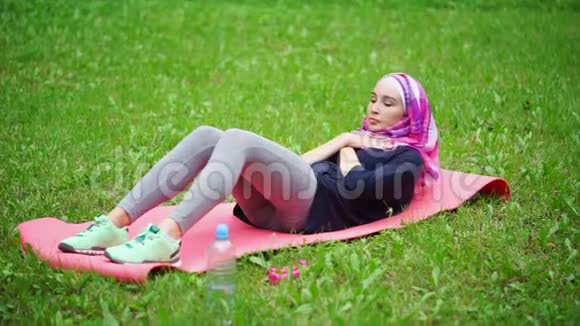 一名身穿罩袍的穆斯林妇女在公园里锻炼以加强新闻视频的预览图