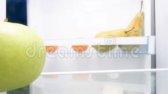 年轻女子打开冰箱咬绿苹果4k镜头视频的预览图