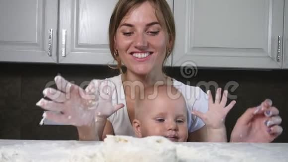 年轻的母亲和她的孩子在桌子上准备面团拍手享受他们在一起的时光家庭视频的预览图