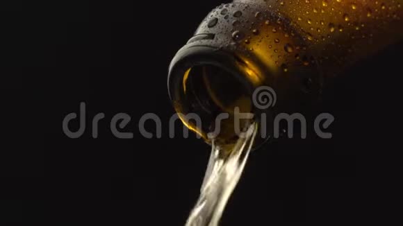啤酒在黑色背景下缓慢地从棕色瓶子中倒入玻璃视频的预览图