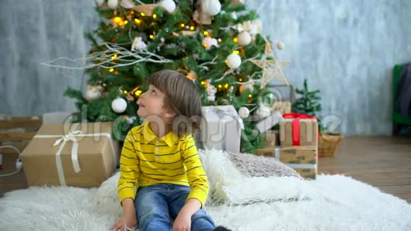 圣诞早晨可爱快乐的小男孩的肖像家庭内部有节日装饰和冷杉视频的预览图