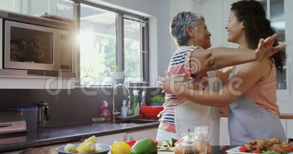 母亲和女儿拥抱在厨房里视频的预览图