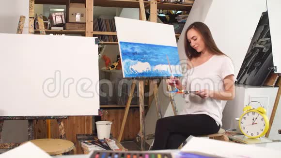 女画家手里拿着调色板画着海浪的油彩画视频的预览图