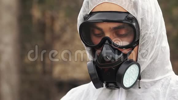 穿着防毒面具和生物危害服的男人看不起在平板电脑上记笔记视频的预览图