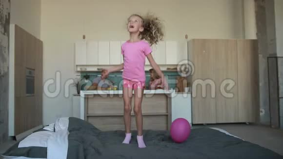 穿着睡衣在床上蹦蹦跳跳的可爱小女孩视频的预览图