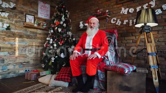 精力充沛的圣诞老人竖起大拇指坐在装饰华丽的房间里的扶手椅上视频的预览图