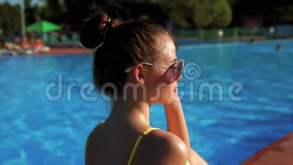 穿着时尚游泳衣在游泳池附近日光浴的苗条女人视频的预览图