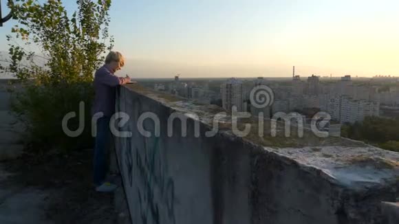 写在城市上空日落时站在摩天大楼屋顶上的人视频的预览图