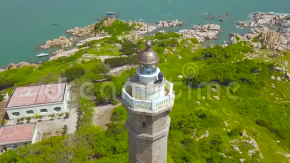 鸟瞰蓝海岩石岛上的海景灯塔和摩天大楼绿色无人机观景灯塔视频的预览图