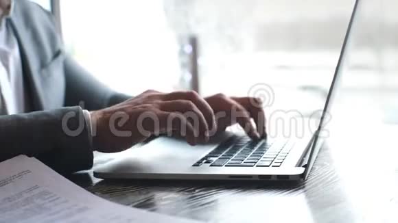 在阳光办公室工作的商人在现代笔记本电脑的特写男性手在笔记本键盘上打字视频的预览图