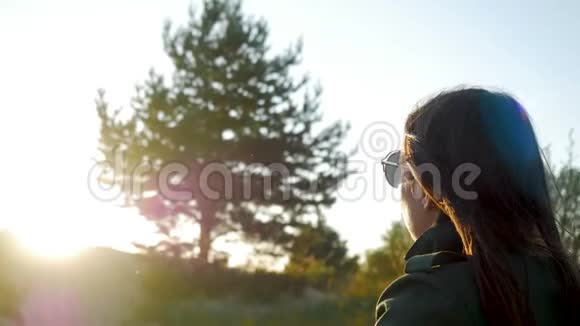 日落时分留着长发和太阳镜的女孩正坐在夹克里视频的预览图