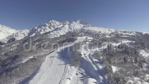 有着长长的滑雪道和电梯的白雪皑皑的山丘的冬季景观视频的预览图