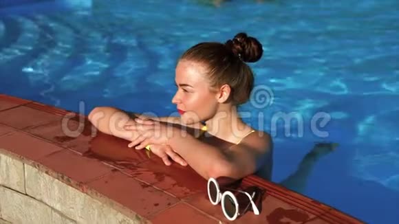 一个穿着泳衣的漂亮女人在炎热的夏天在游泳池里放松视频的预览图