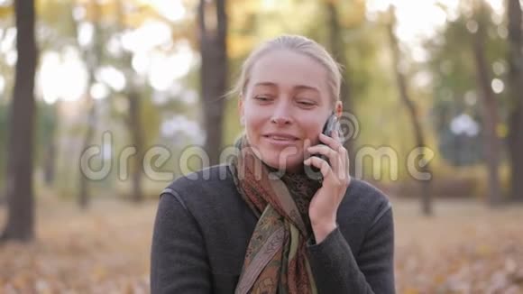 坐在美丽的秋天公园里的女人在打电话视频的预览图