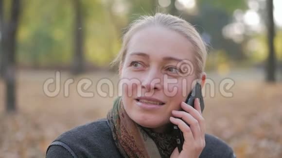 坐在美丽的秋天公园里的女人在打电话视频的预览图