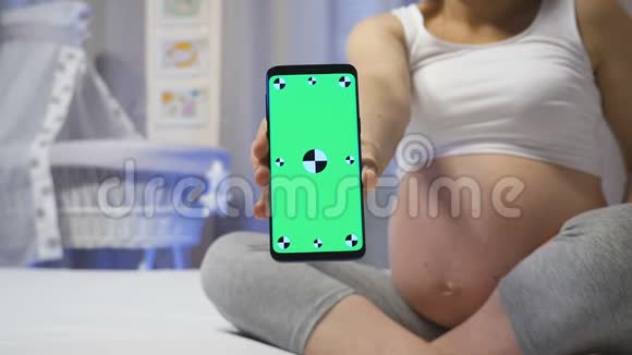 孕妇用绿色屏幕显示智能手机视频的预览图