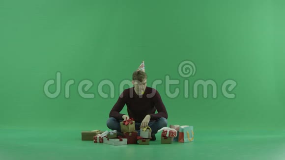男人在圣诞礼物中打开空礼物绿色的彩色钥匙背景视频的预览图