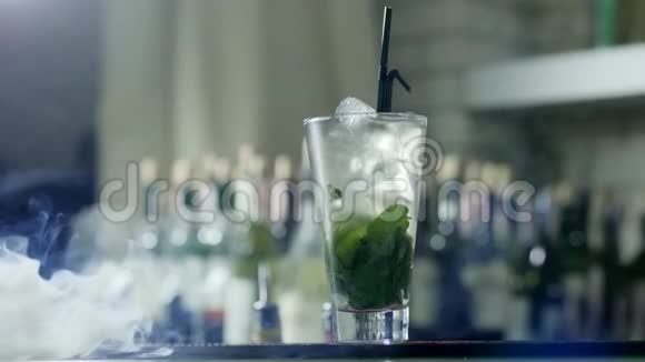 冰镇饮料用冰块和绿色薄荷叶放入大玻璃杯中用黑色塑料吸管站在烟柜上视频的预览图