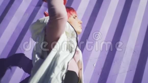 独立年轻女性的肖像粉红色的头发摆在紫色的容器背景上慢动作视频的预览图
