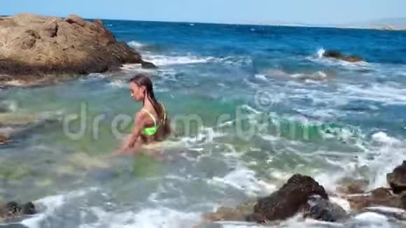 年轻女孩在荒凉的岩石海滩游泳视频的预览图