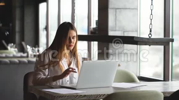 女商人在窗户附近的一家咖啡馆里用笔记本电脑工作视频的预览图
