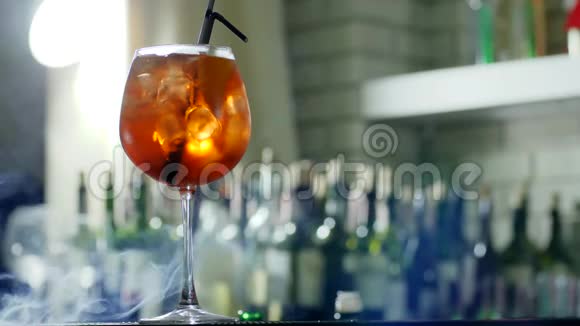明亮的酒精饮料与冰块和塑料吸管在酒杯特写进入容易雾霾的未聚焦背景视频的预览图