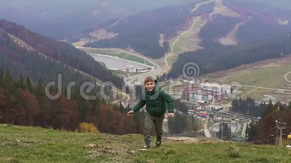 一个漂亮的男孩在山顶上奔跑对着镜头微笑秋的概念Bukvel视频的预览图