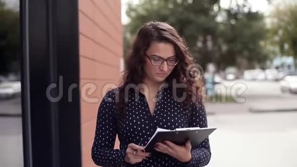 年轻漂亮的商务女性靠近商务大厦签署工作文件视频的预览图