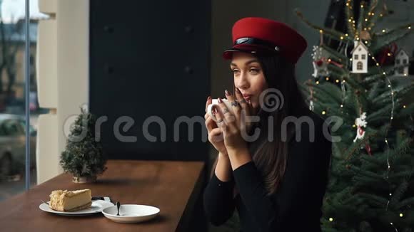 戴红帽子的迷人女人在舒适的咖啡馆里喝咖啡视频的预览图