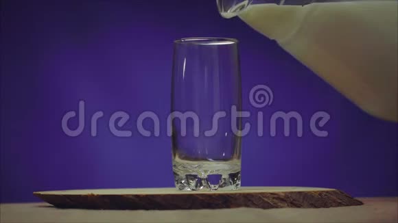 蓝色背景上有牛奶的杯子透明库什文的牛奶倒入玻璃杯中视频的预览图