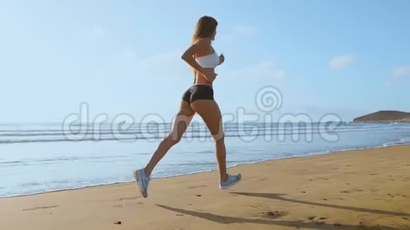 女子运动员剪影奔跑在沙滩上冲刺海浪拍打海滨晨景背景慢动作视频的预览图