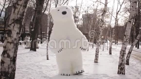 巨大的木偶熊走在白雪覆盖的白桦林上视频的预览图
