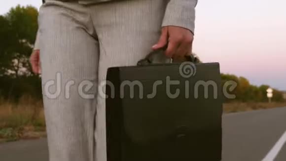 女商人手里拿着黑色的公文包穿着裤子穿着沥青上的夹克关上了门视频的预览图