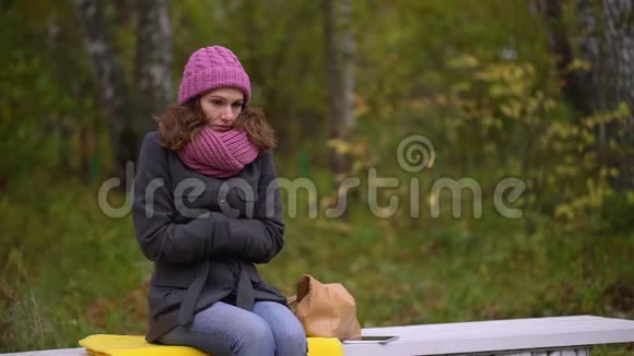 凄美女子冻在秋公园寒秋她感到寒冷并试图保暖慢动作视频的预览图