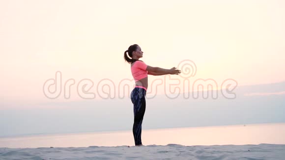 健康的年轻美女在沙滩上海边河边黎明时分黎明时分练习瑜伽视频的预览图