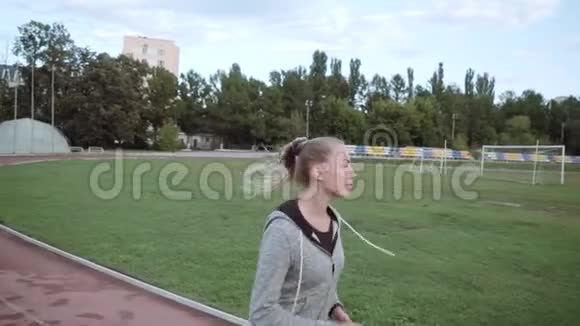 那个女孩沿着跑步机在体育场周围跑步慢动作视频的预览图