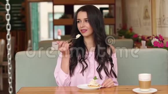 漂亮的年轻女人坐在咖啡馆里吃蛋糕视频的预览图