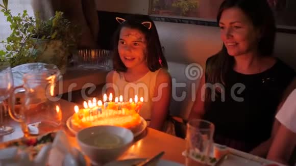 可爱的小女孩在家开生日聚会在生日蛋糕上吹蜡烛孩子们的生日派对五颜六色视频的预览图
